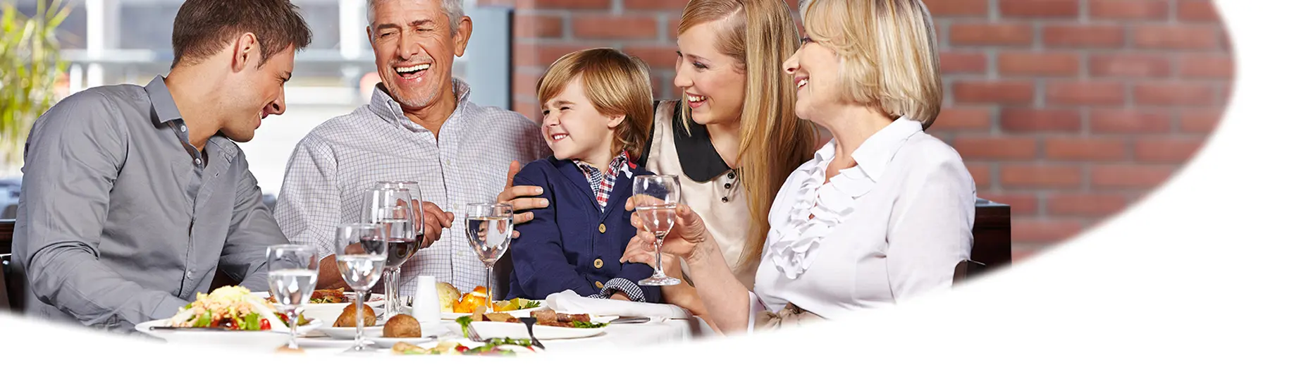 Hotel und Gastronomie im Wohnpark Martins Höhe. Introbild zeigt eine junge Familie, die lachend an einem Tisch sitzt.